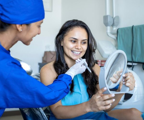 patient-smiles-looks-into-mirror-while-being-seen-by-dentist_505281-329